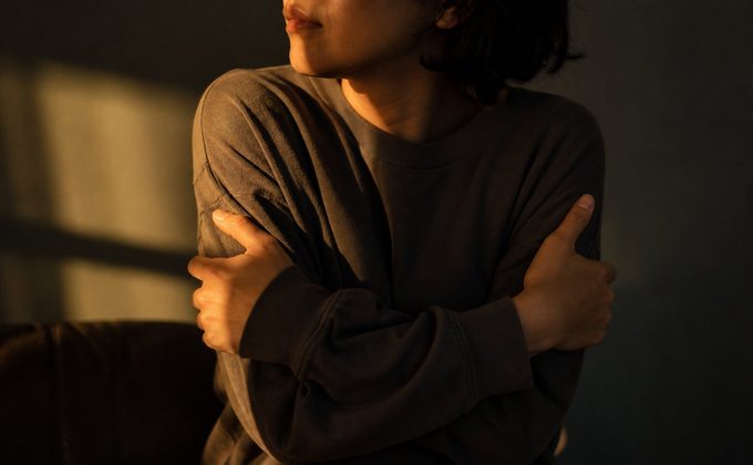 A person gently hugging themselves for comfort